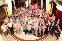 A large group of IU School of Dentistry alumni with an IU flag gathered in a lobby.